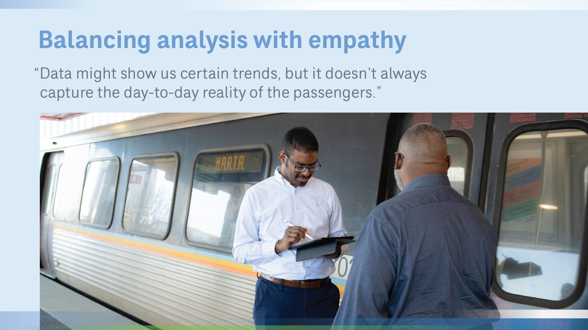 2 men with tablet standing next to a train