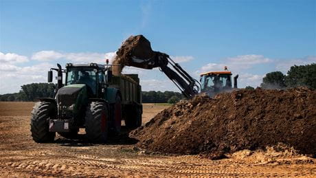 Front loader loading biosolids in dump truck
