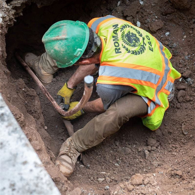 construction worker replacing a lead pipe with a new pipe